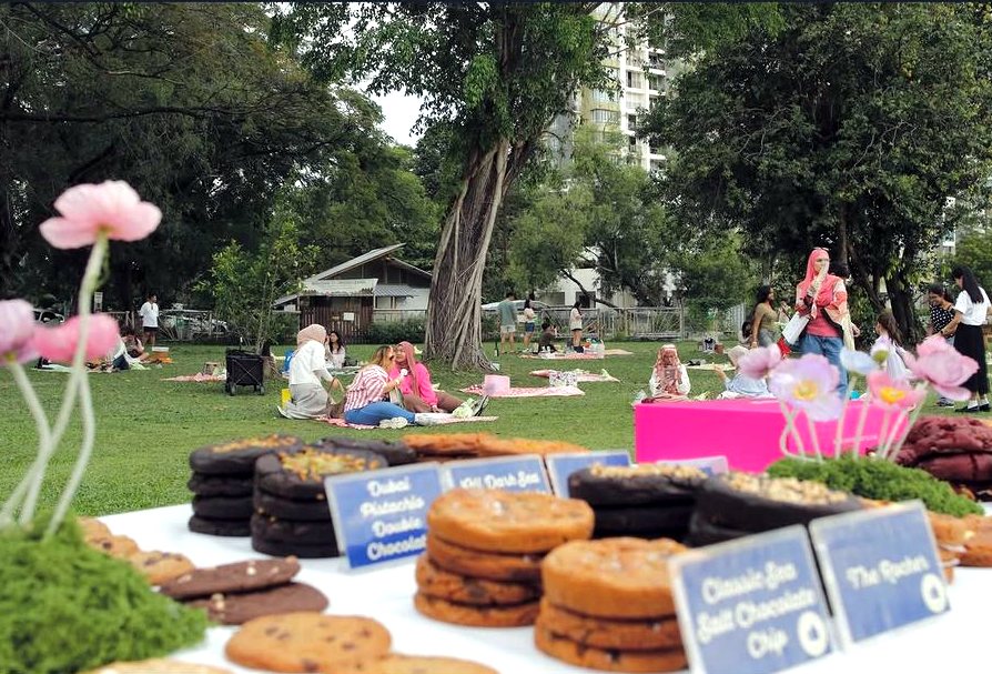 Picnic guests behind a table of labelled cookies