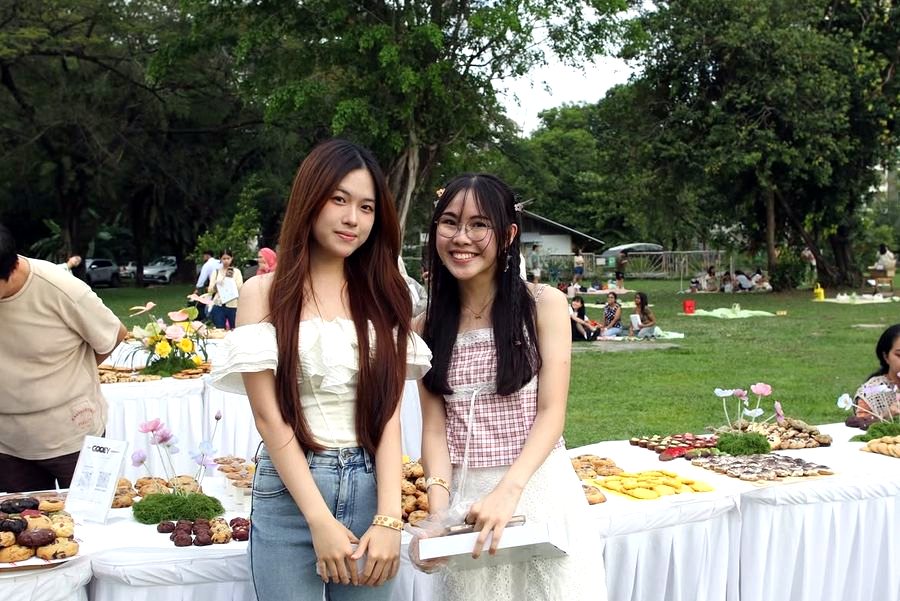 Two friends posing beside the cookie tables