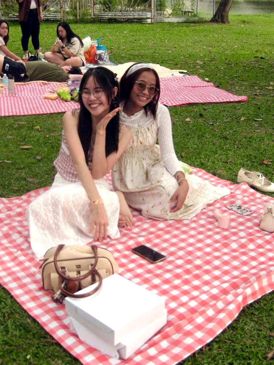 Two friends posing on a gingham picnic mat