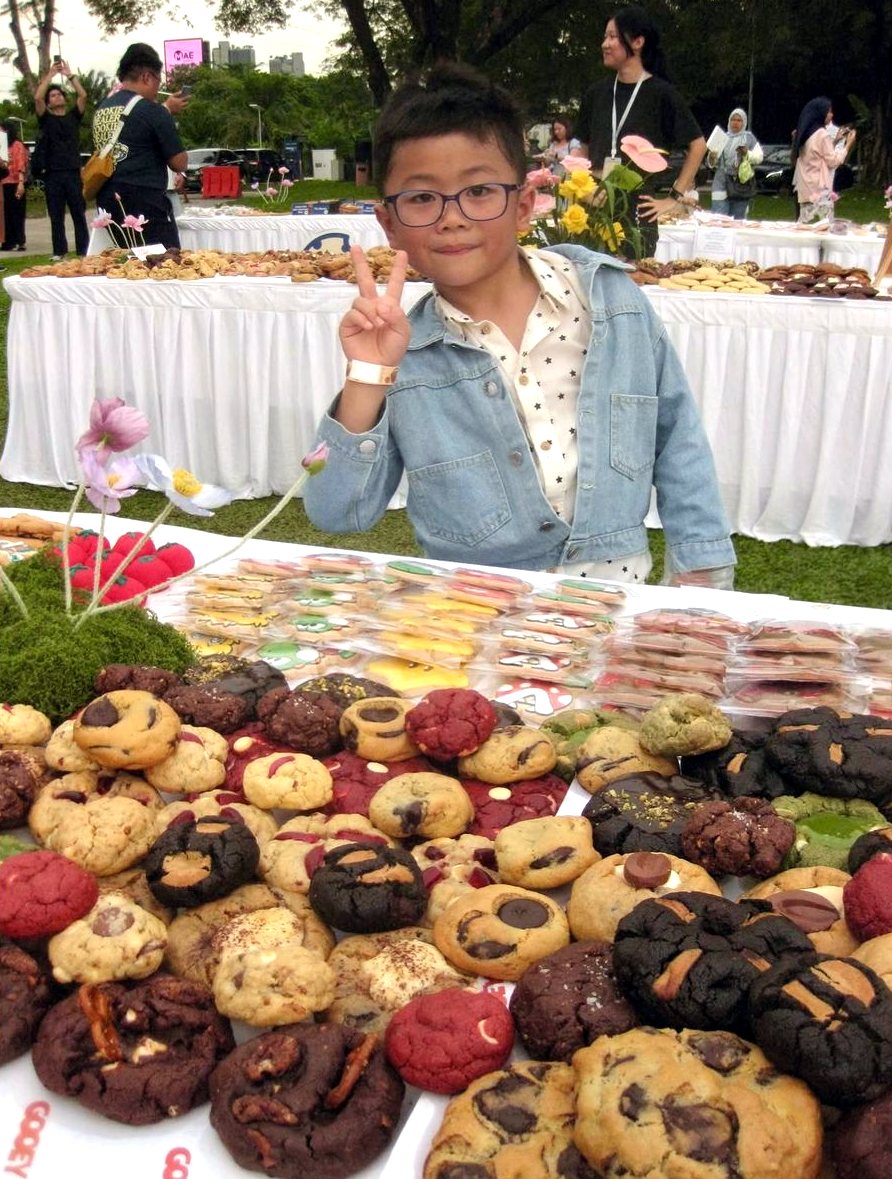 A child giving a peace sign behind a pile of cookies